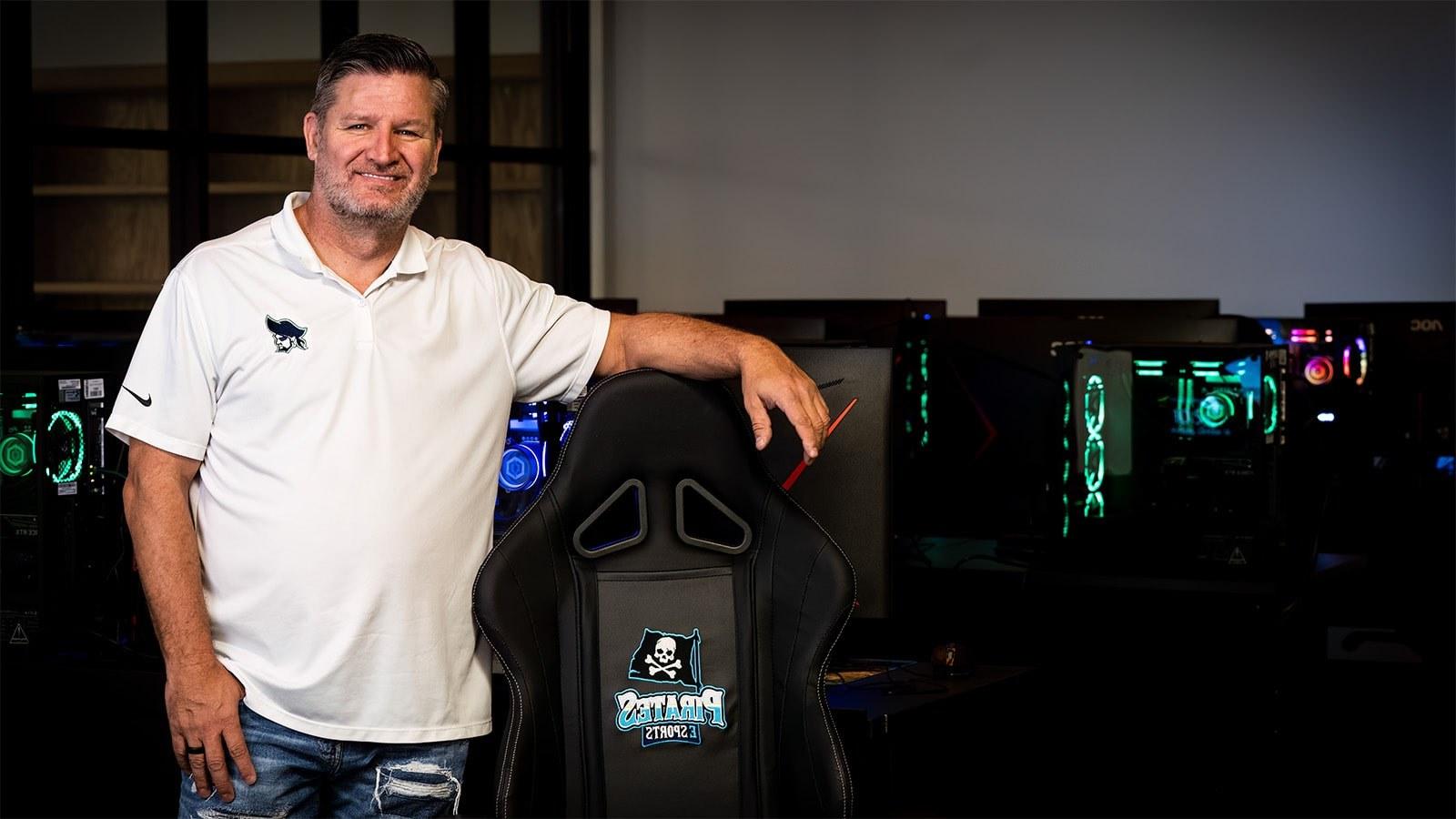Scott Brumfield stands in front of gaming PCs. He is next to a PSC Pirates gaming chair and is wearing a Pirates shirt.