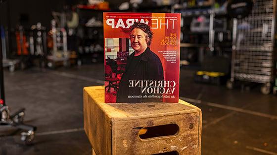 A physical copy of the October 2023 issue of 'TheWrap' is standing upright on a stack of wooden crates in a film studio setting.